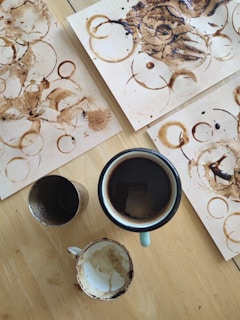 An artfully arranged portfolio layout on a wooden table with coffee stains and notes.