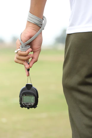 Hands holding a stopwatch and a notebook with mental training notes.