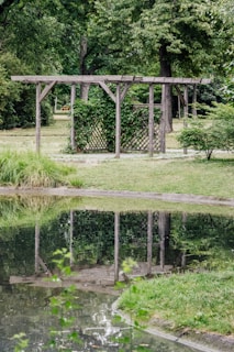 Elegant white pergola overlooking a serene garden pond with colorful flowers