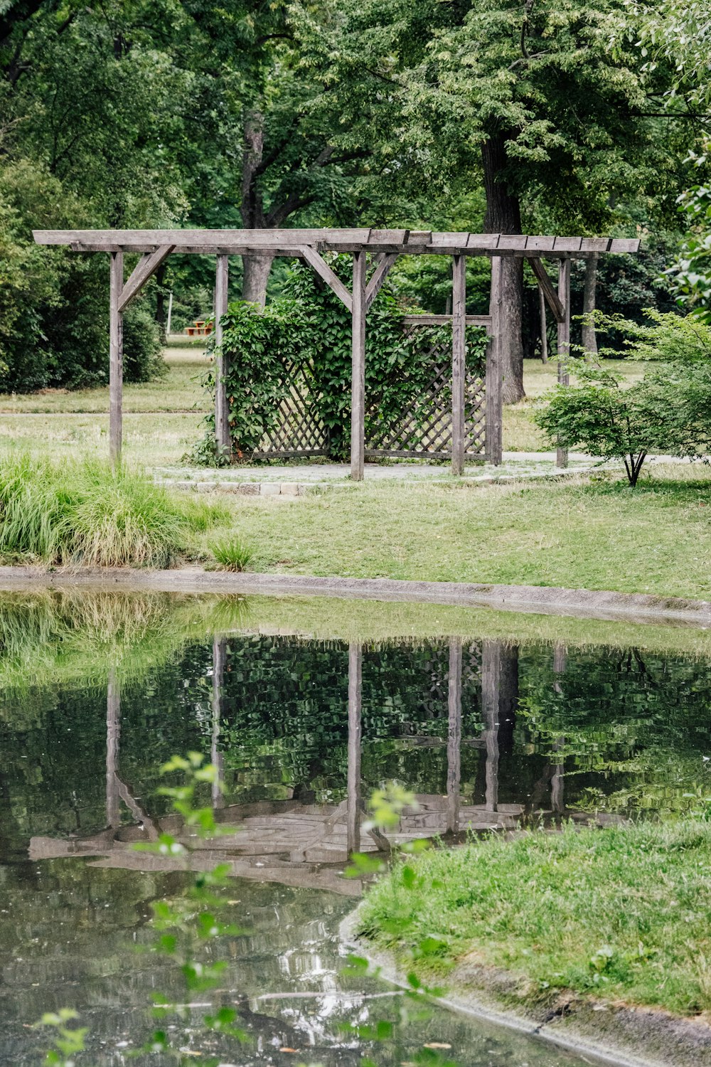 a gazebo in the middle of a grassy area next to a body of water