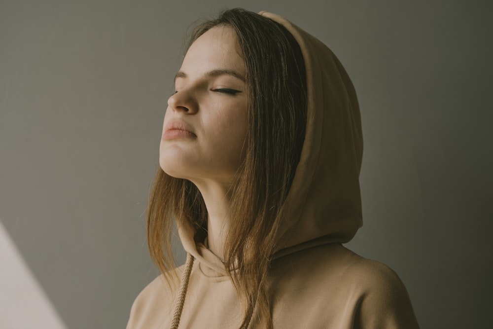 a woman with her eyes closed wearing a hoodie