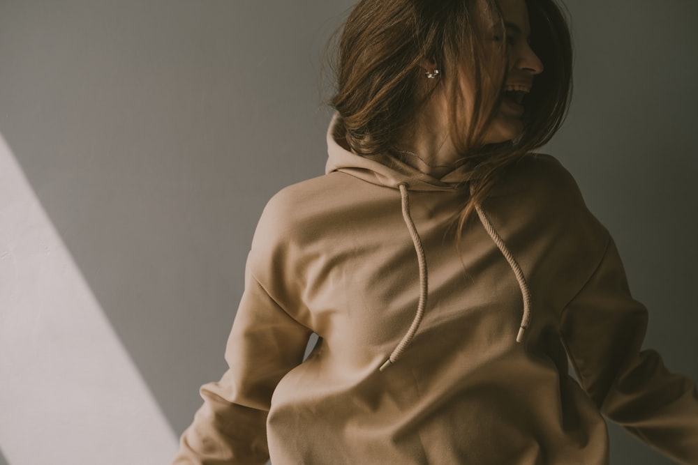 a woman in a tan hoodie standing in a room
