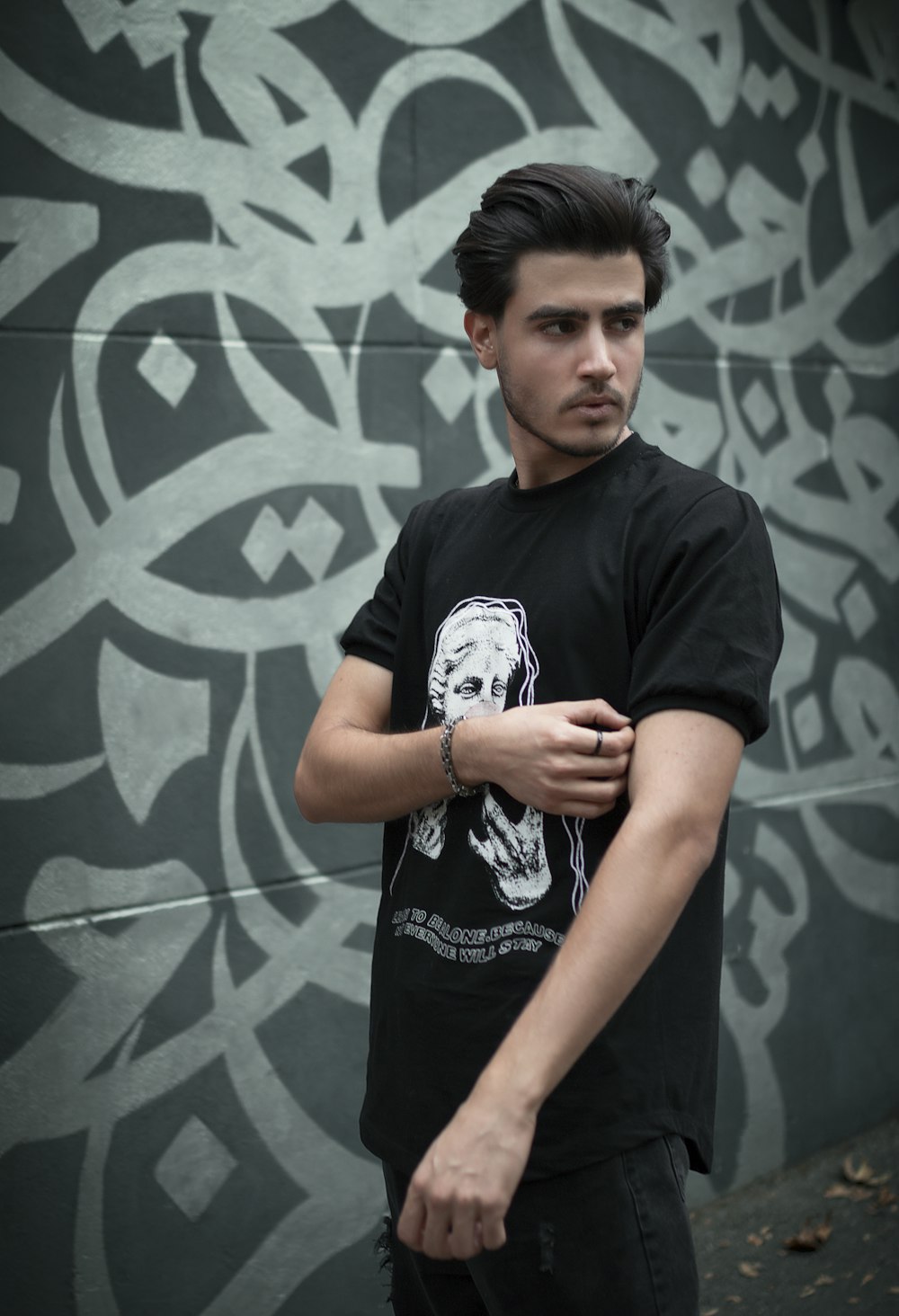 a man standing in front of a wall with graffiti on it