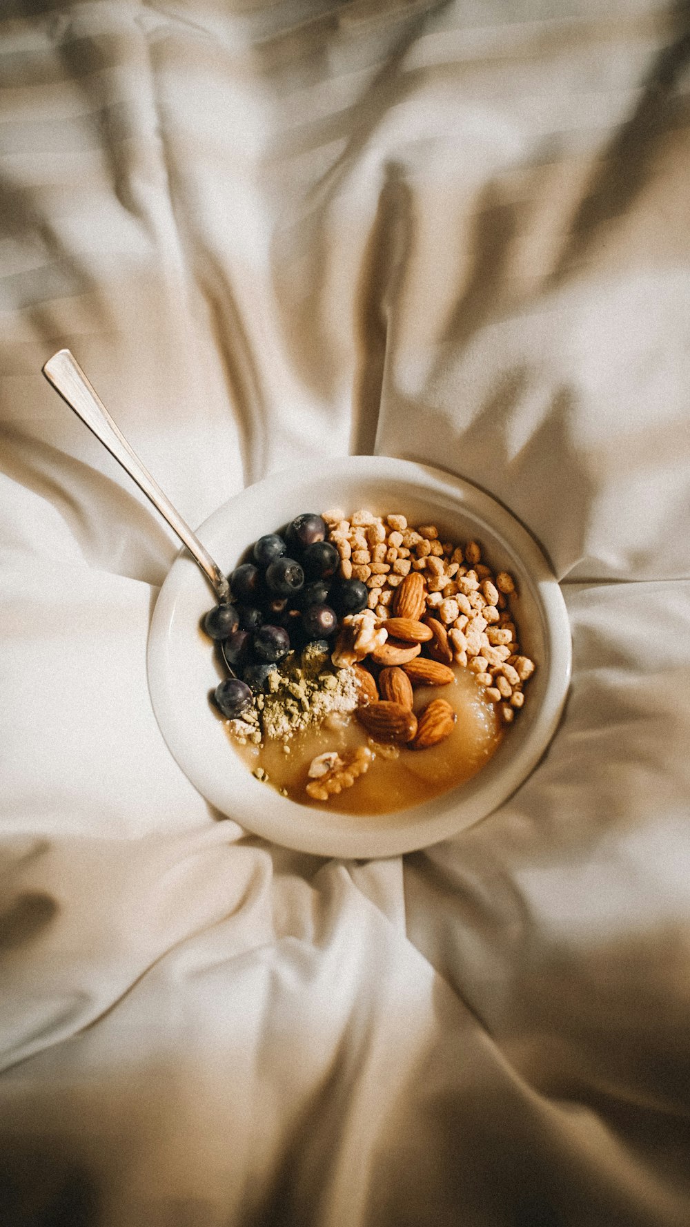 a bowl of cereal and berries on a bed