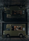 A vintage-style food truck with a pale green color is parked in an urban setting, offering a variety of pastries and beverages. The truck's interior is illuminated, highlighting pastries displayed inside. A person inside the truck is attending to the offerings or setting up. The truck bears the name 'LADUREE' on its side. Its exterior design features classic elements, and a menu board is visible.