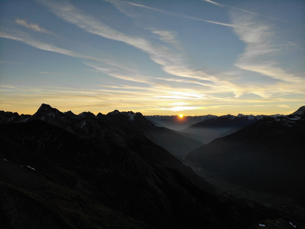 the sun is setting over a mountain range