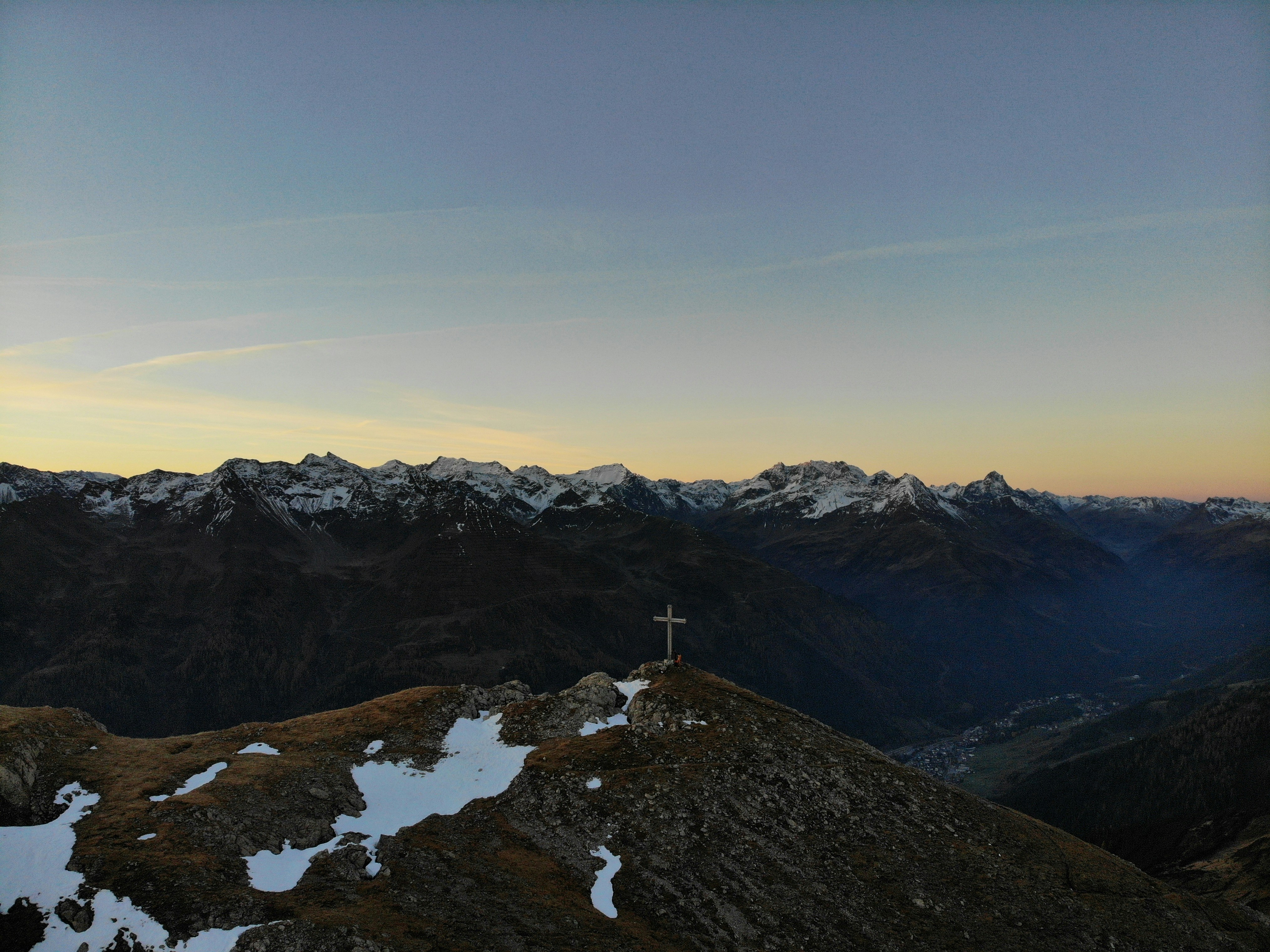 a cross on top of a mountain at sunset