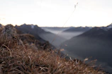 A serene mountain landscape at dawn with mist rolling over the peaks.