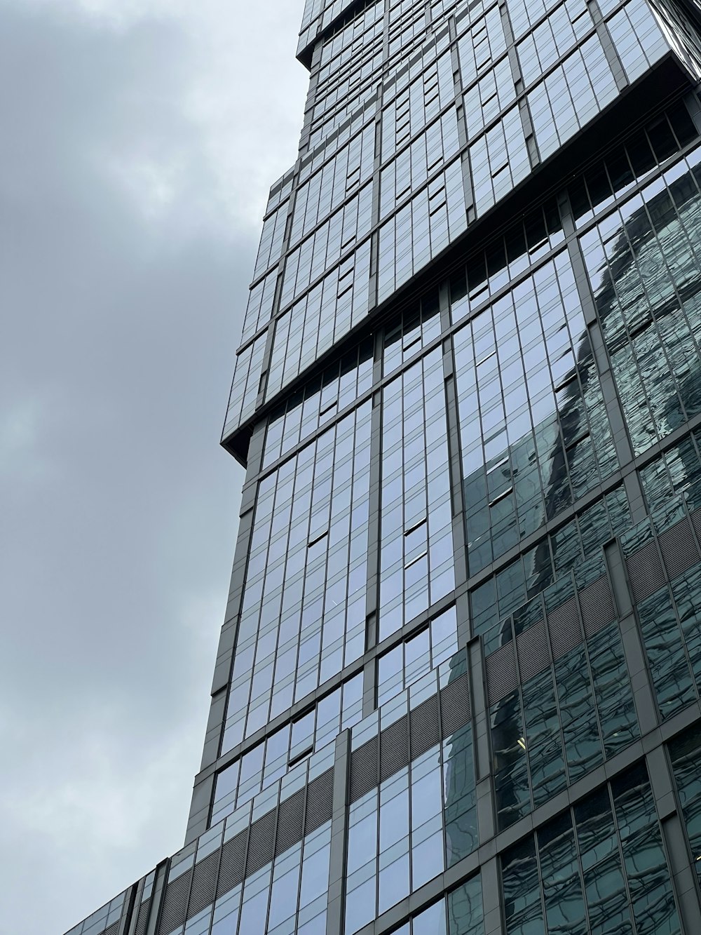 a very tall glass building with a clock on it's side