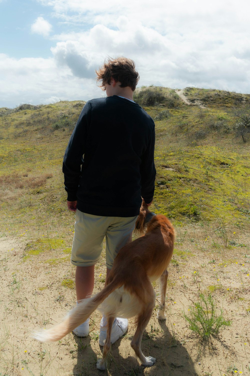 a man standing next to a brown and white dog