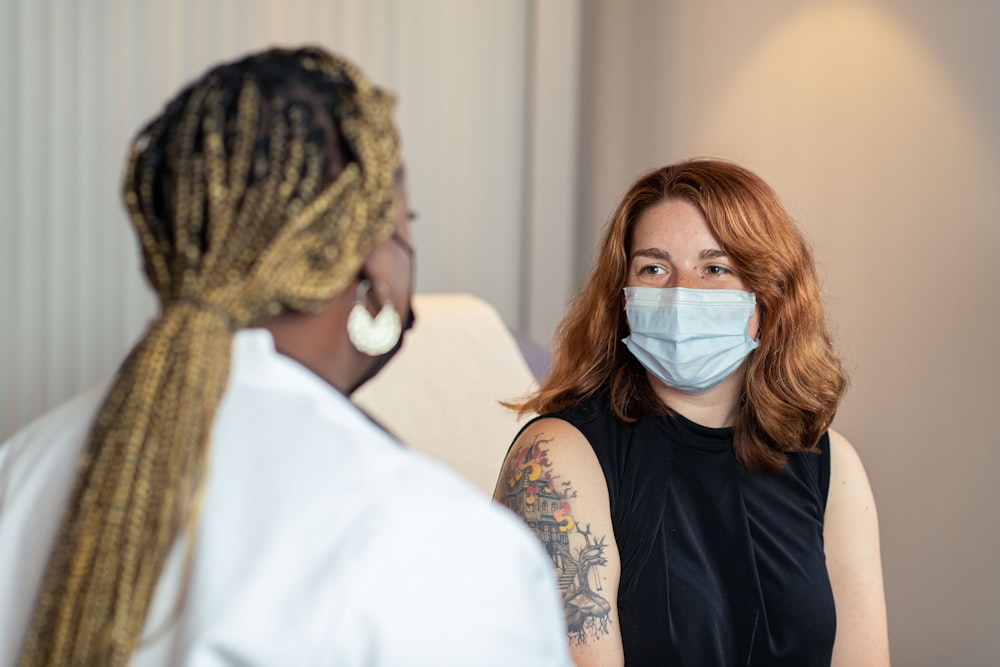 a woman with a face mask talking to another woman