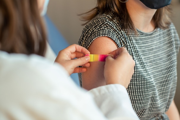 Close-up of hands applying a bandage on an elderly person's arm in a clinical setting.