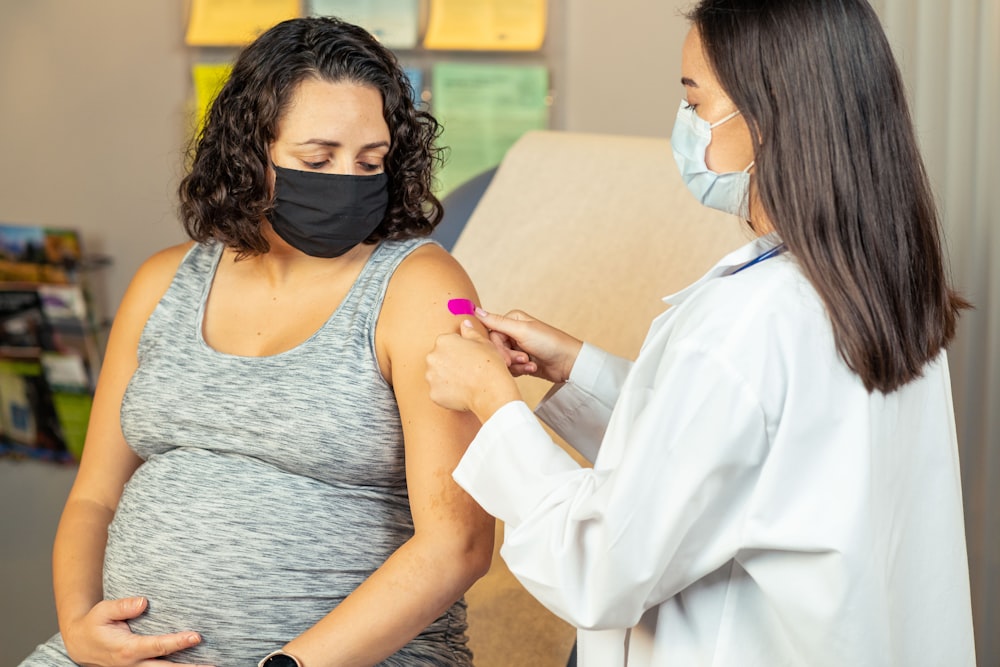 a pregnant woman wearing a face mask is being examined by a doctor