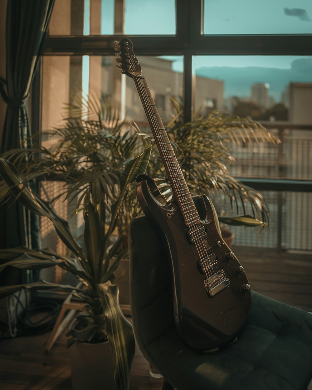 uma guitarra sentada em uma cadeira em frente a uma janela