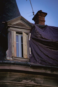 Close-up of emergency tarping on a leaking roof at dusk.