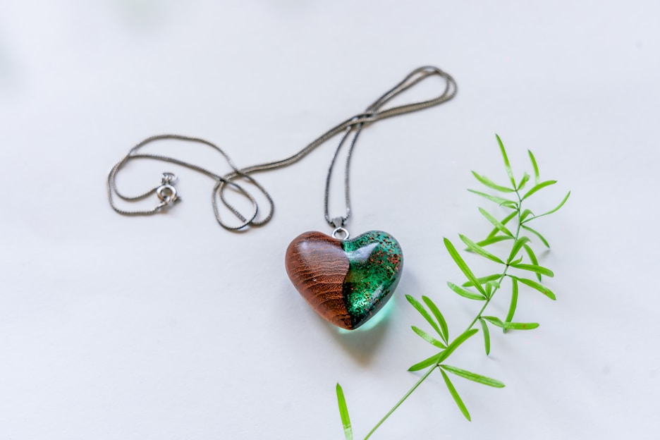 Close-up of a handcrafted resin pendant containing pet ashes and hair, glowing softly in warm light