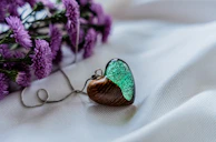 Warm-toned photo of a wooden necklace pendant resting on a bed of dried flowers.