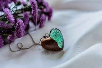 A close-up of a cracked glass heart pendant lying on a bed of scattered letters.