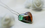 Close-up of a resin pendant with embedded dried flowers on a soft beige background.