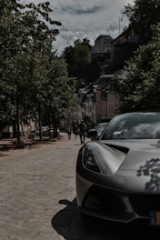 A sleek luxury car parked on a cobblestone street in Prague at sunset.