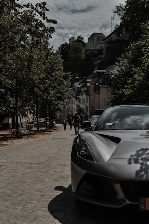 A sleek luxury car parked on a cobblestone street in Prague at sunset.