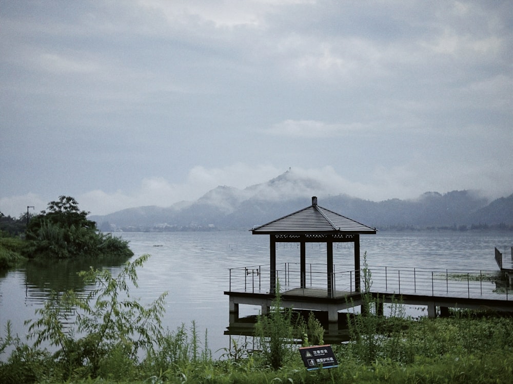 a gazebo sits on the shore of a lake