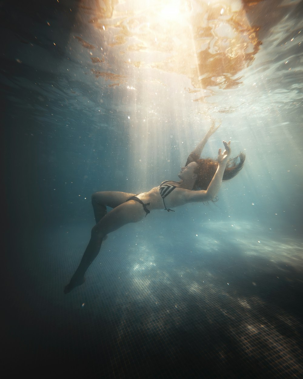 a woman in a bikini swims under water