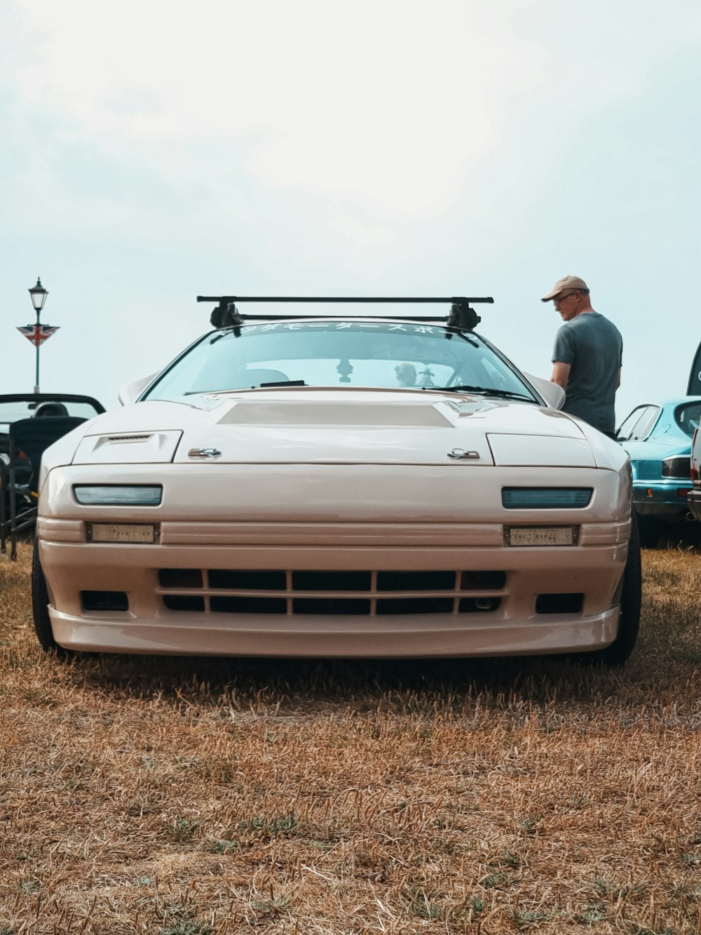 a man standing next to a car in a field