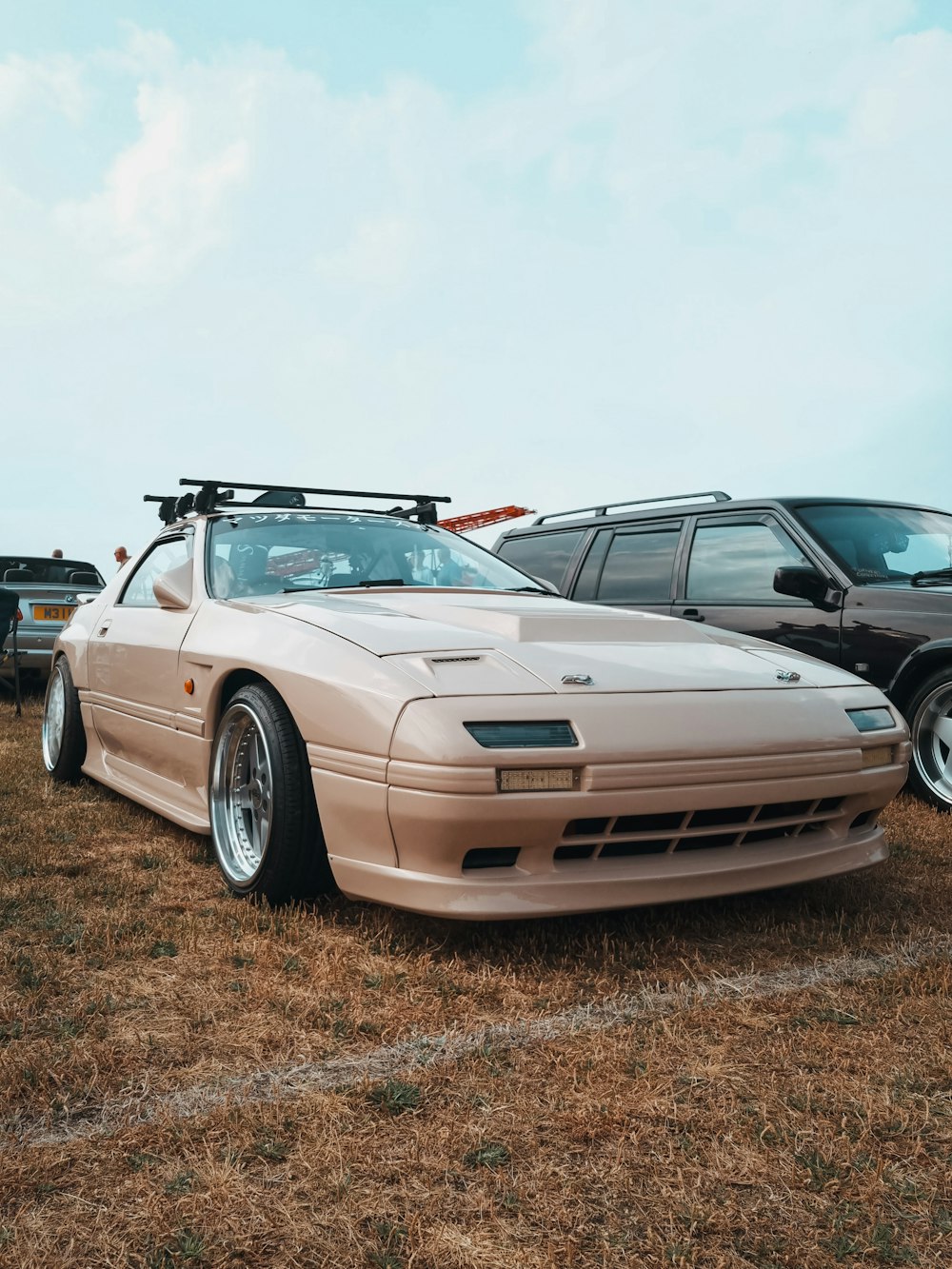 a beige sports car parked in a field