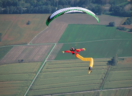 a person is parasailing over a field of crops