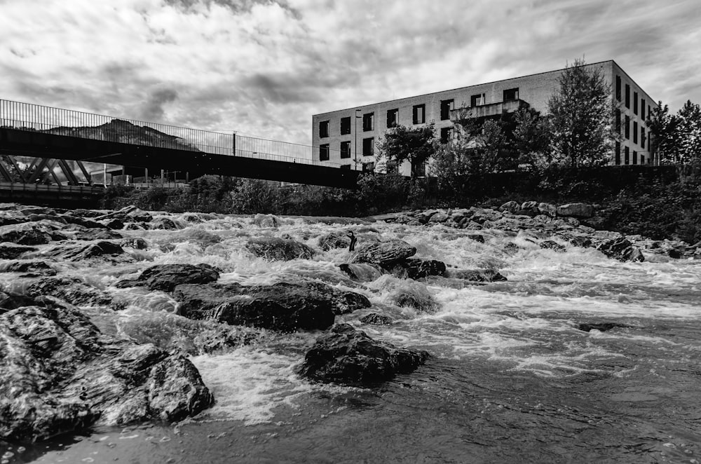 a black and white photo of a river and a bridge