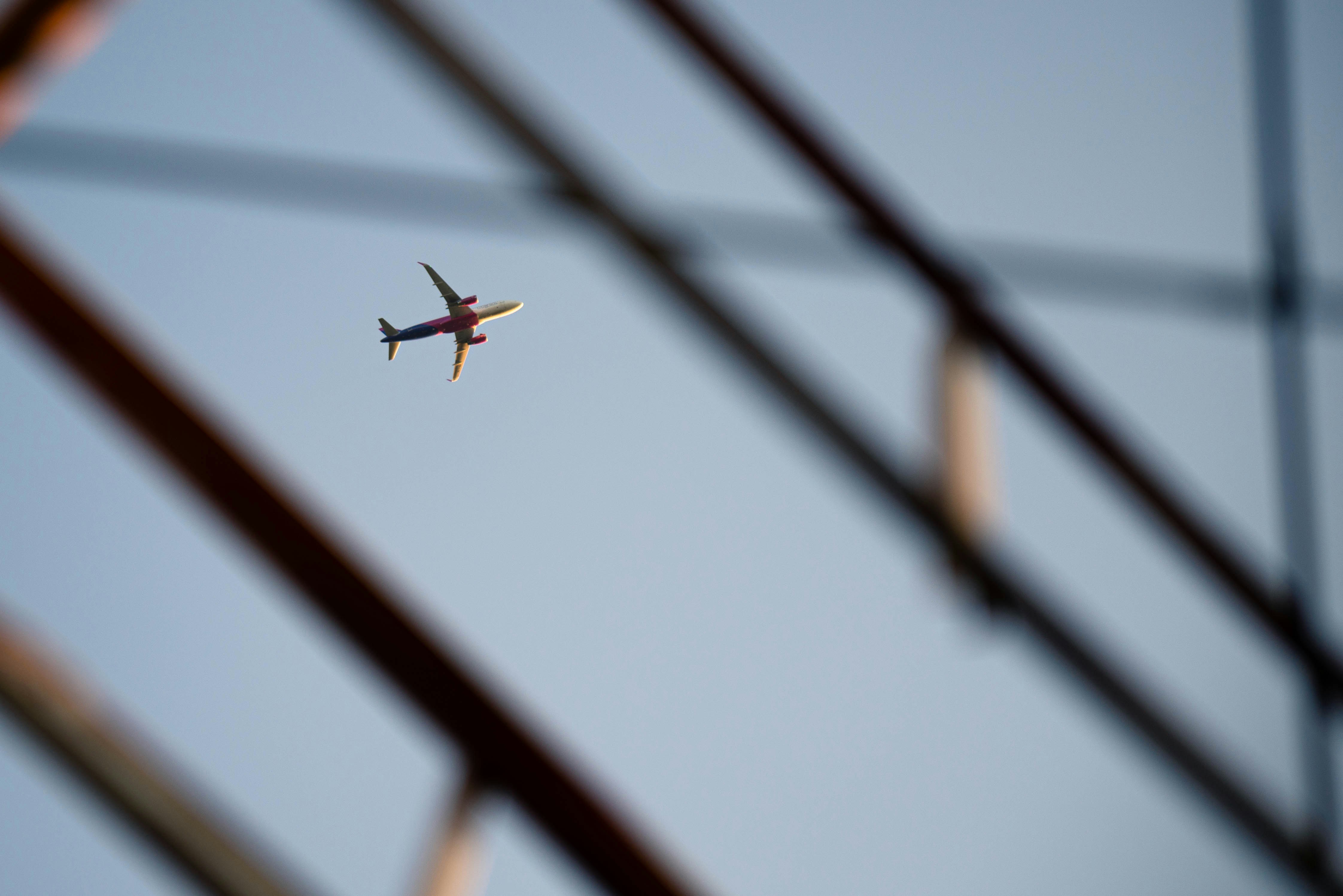 Ein Flugzeug fliegt am Himmel über Stromleitungen