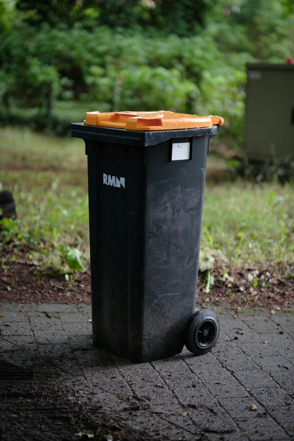 a black trash can sitting on top of a sidewalk