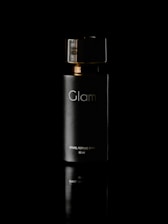 A sleek, dark bottle labeled 'Glam' with gold accents is centered against a black background. The reflective surface beneath adds a sense of elegance and luxury to the presentation.