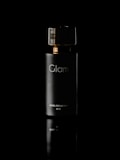 A sleek, dark bottle labeled 'Glam' with gold accents is centered against a black background. The reflective surface beneath adds a sense of elegance and luxury to the presentation.