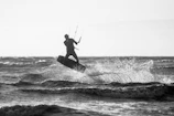 Close-up of a kitesurfer launching off a wave, water droplets sparkling in the sunlight.