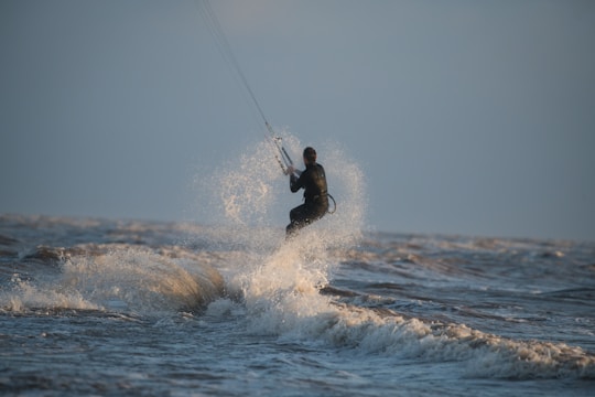 An instructor guiding a student on a kite surf board.