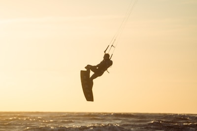 A kite surfer catching air over the calm waters of Kalpitiya lagoon at sunset.