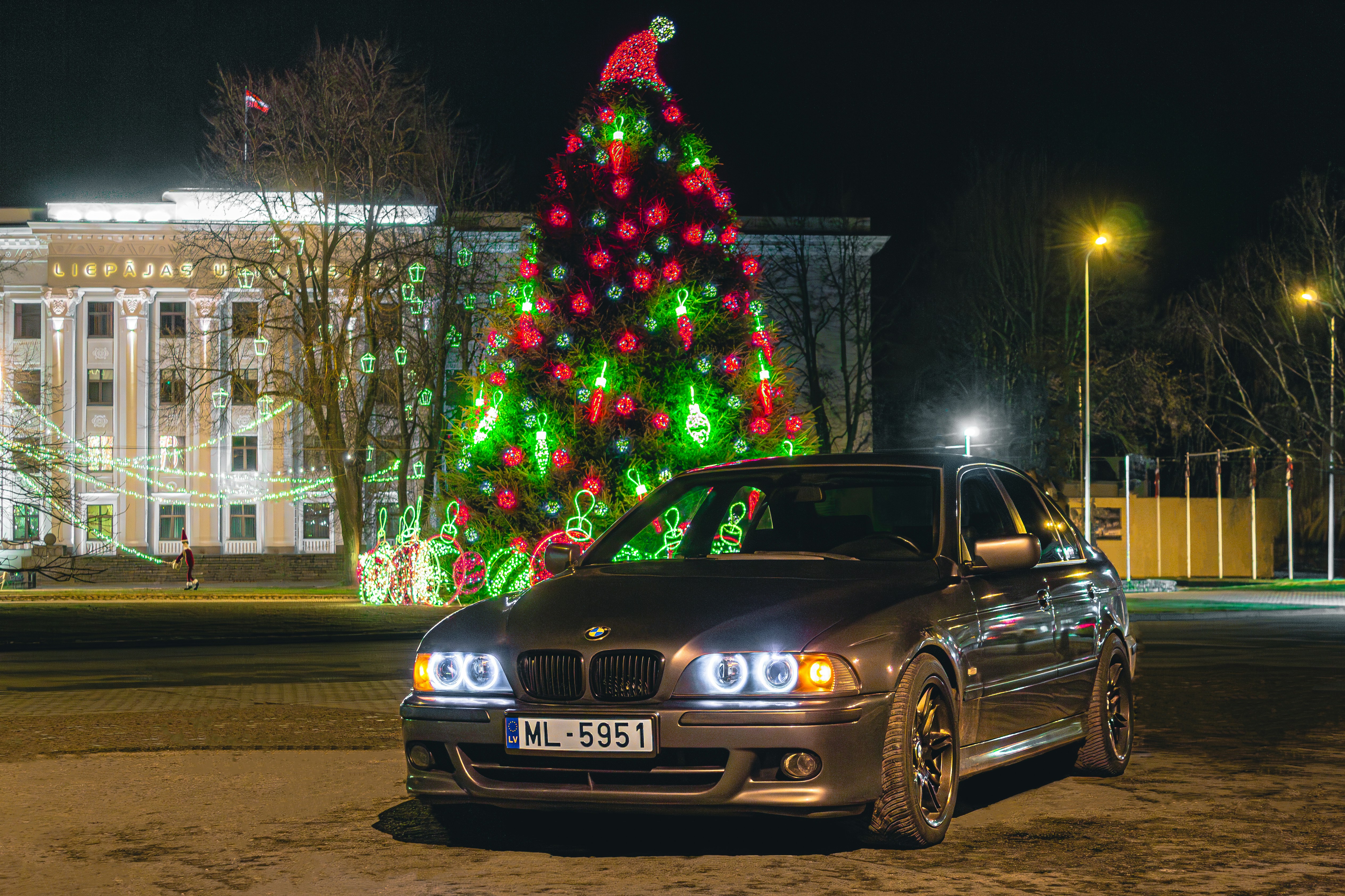 BMW parked in front of lit-up Christmas tree