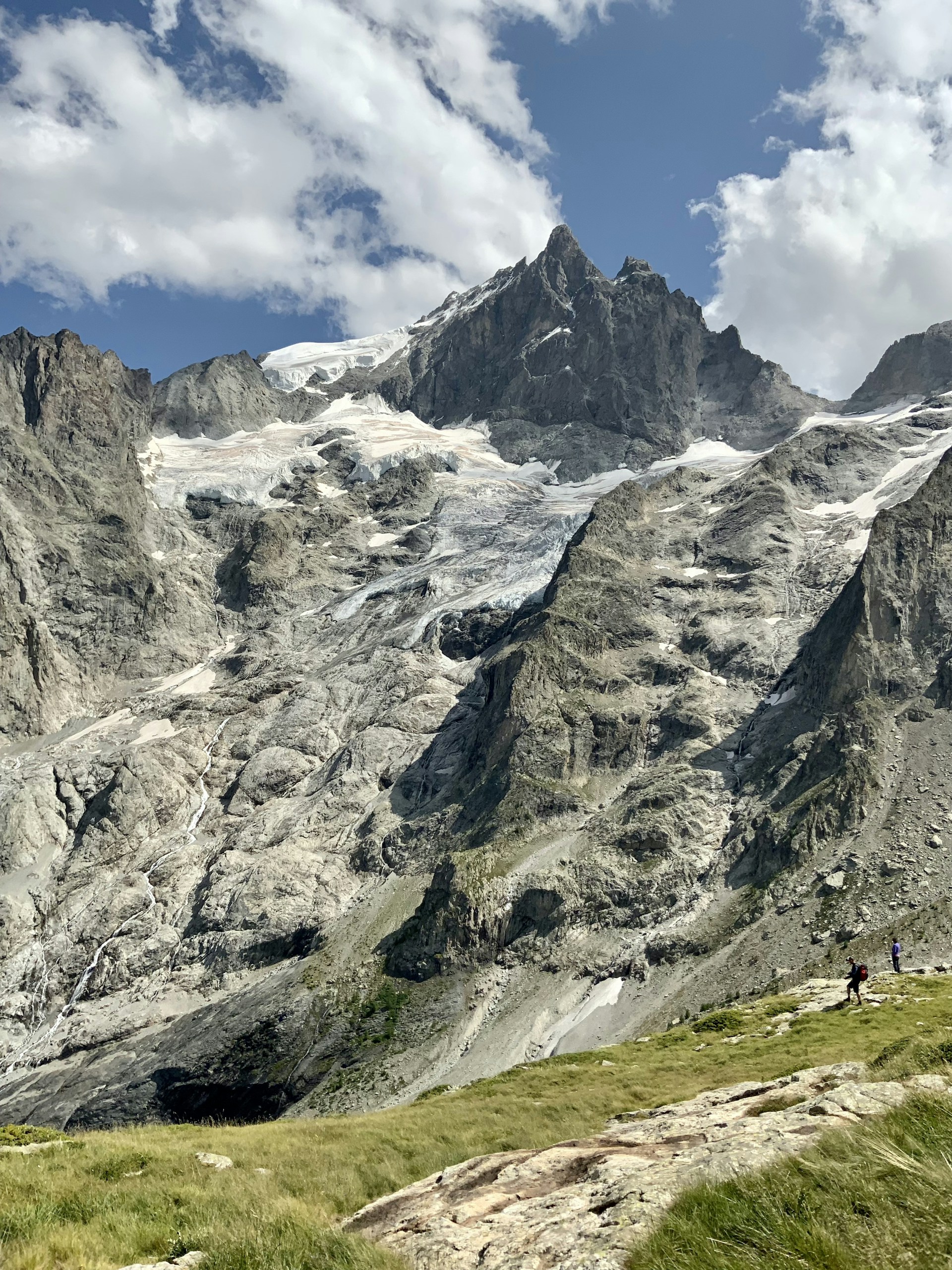 A majestic mountain landscape with hikers enjoying a clear day, surrounded by lush green forests and blue skies.