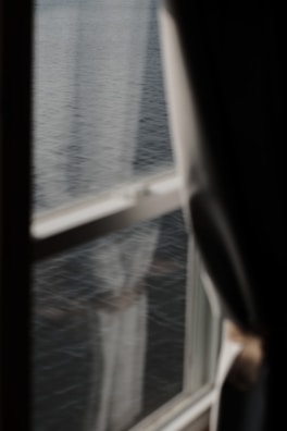 A peaceful window view framed by sheer curtains in soft cream.