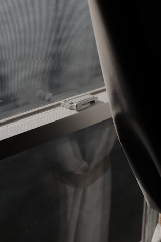 A large mosquito net installed on a wide window with sunlight filtering through.