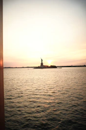 A serene video background showing the Statue of Liberty and Ellis Island at sunset.