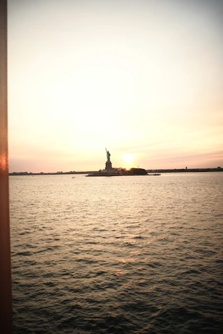 A serene video background showing the Statue of Liberty and Ellis Island at sunset.