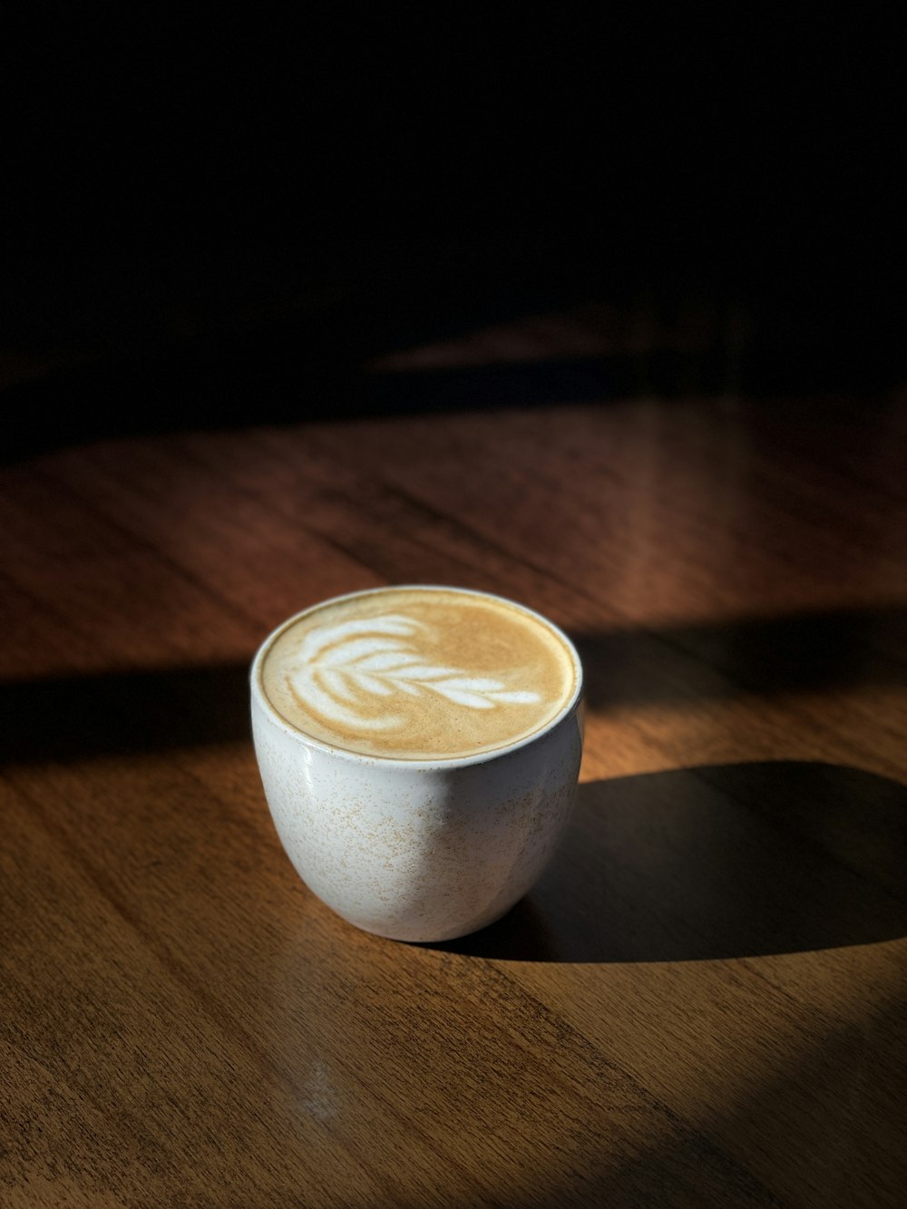 a cup of coffee sitting on top of a wooden table