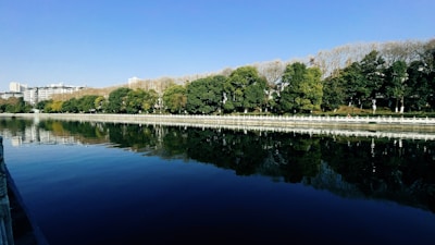 Calm river reflecting vibrant autumn trees under a blue sky.