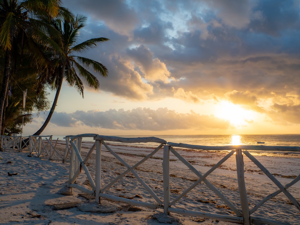 the sun is setting over the beach with palm trees