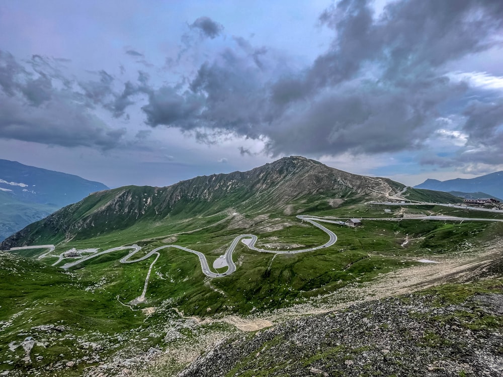 a winding road in the mountains under a cloudy sky