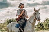 A cowboy praying quietly beside his horse at sunset on a wide open ranch.