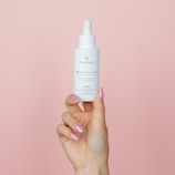 A close-up of hands holding a nourishing hair oil bottle.